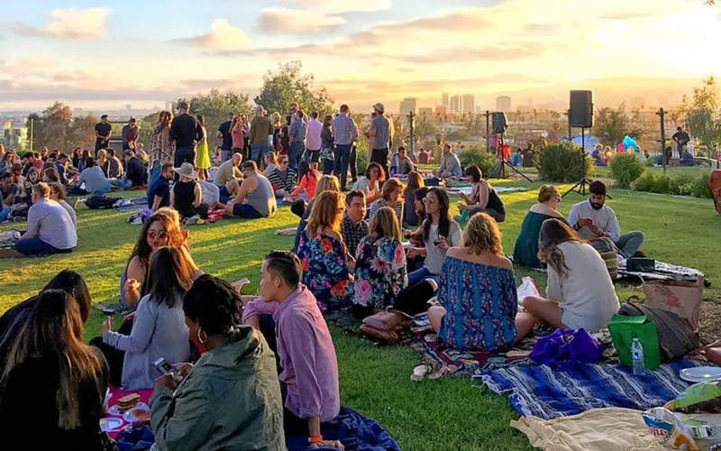 People sitting on the grass tasting wine